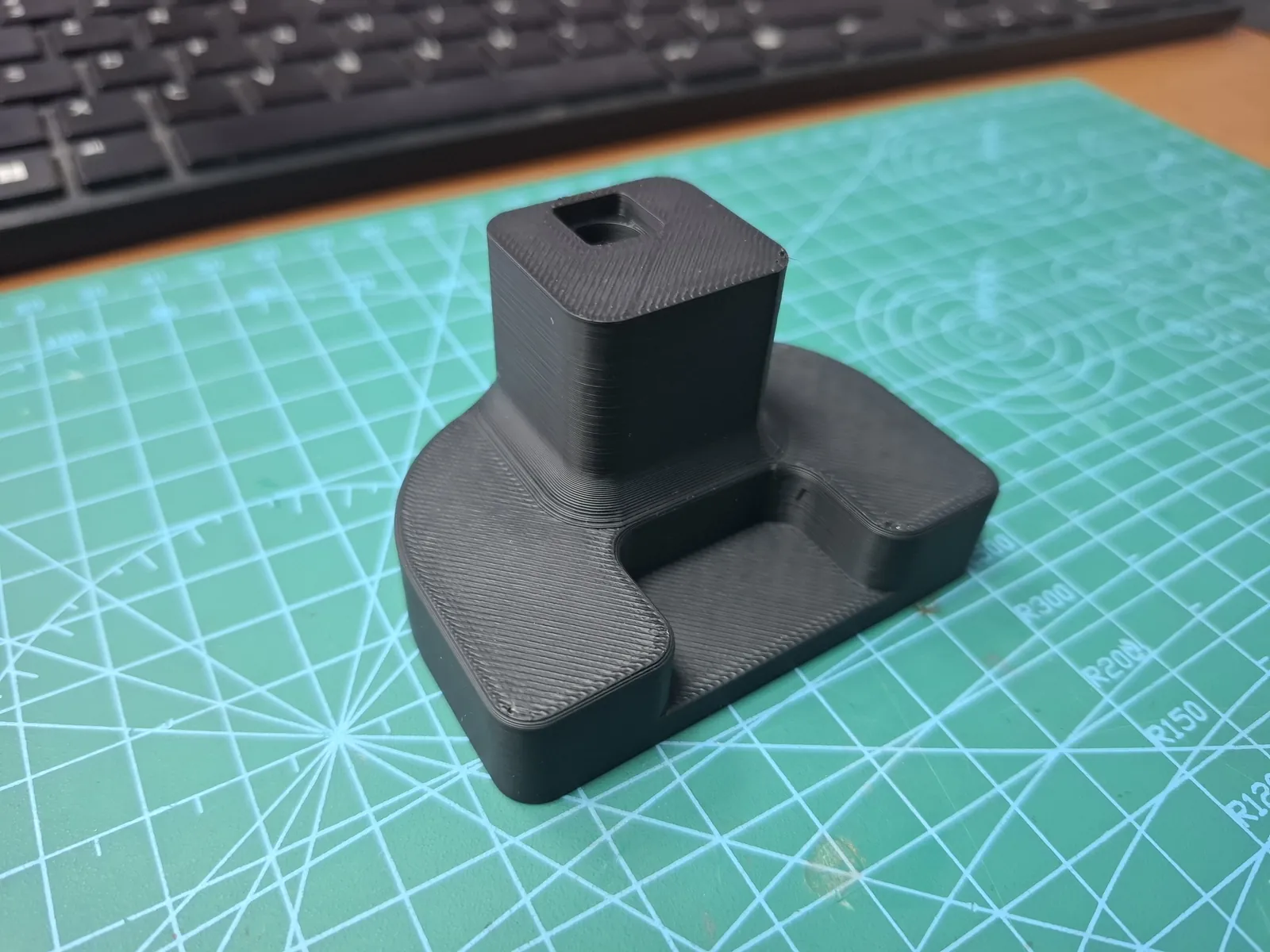Czarny element z wydruku 3D z kwadratowym gniazdem na macie do cięcia